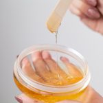 Woman holding bowl of wax for depilation and skin care
